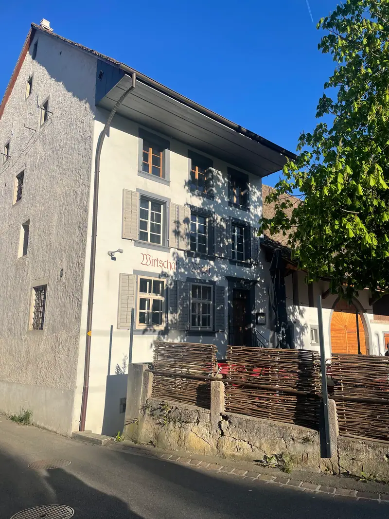 Die Fassade des Rössli mit hellem Rauputz, grauen Fensterläden und dem Schriftzug «Wirtschaft zum Rössli»