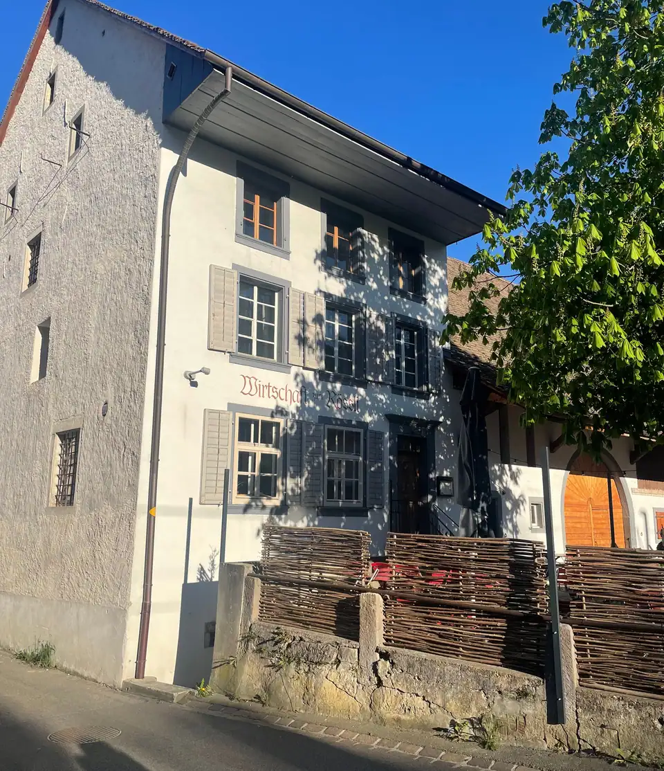 Die Fassade des Rössli mit hellem Rauputz, grauen Fensterläden und dem Schriftzug «Wirtschaft zum Rössli»