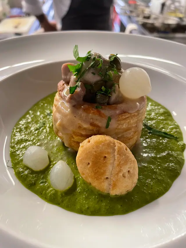 Pastetli auf grüner Sauce mit kleinen Zwiebeln und einem Gebäckstück