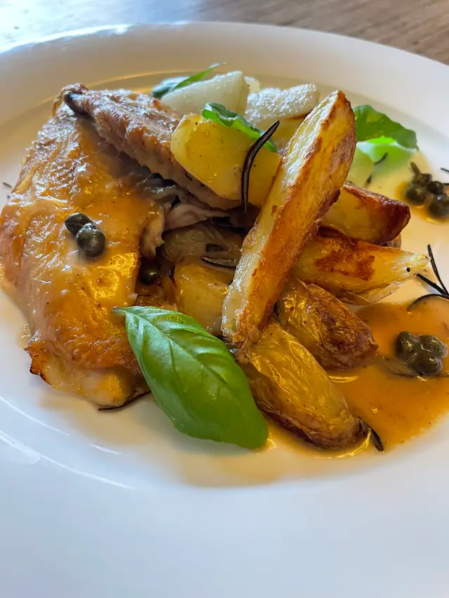 Knusprig gebratenes Poulet mit Kartoffelspalten, Kapern und Basilikum