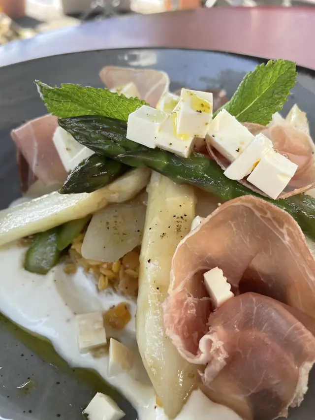 Spargelsalat mit Rohschinken, Feta und Minze auf einem grauen Teller